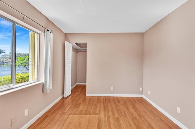 unfurnished bedroom with light wood-type flooring, a closet, and multiple windows