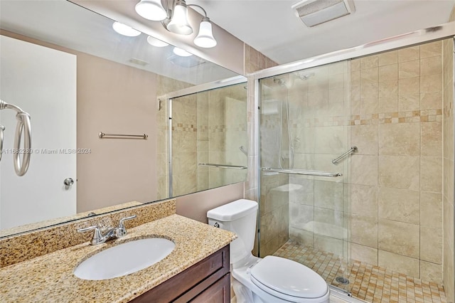 bathroom with vanity, a shower with shower door, and toilet