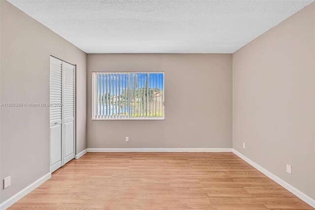 unfurnished bedroom featuring a textured ceiling, light hardwood / wood-style flooring, and a closet