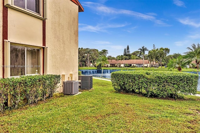 view of yard with a water view and central air condition unit