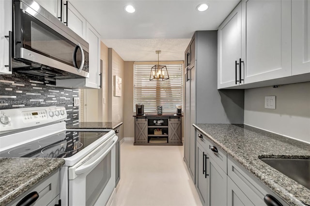 kitchen with hanging light fixtures, a chandelier, backsplash, stone countertops, and white electric stove