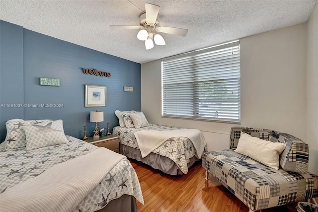 bedroom with hardwood / wood-style floors, ceiling fan, and a textured ceiling