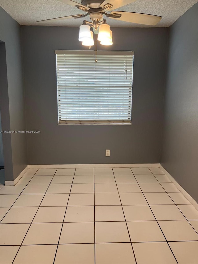 tiled empty room featuring ceiling fan and a textured ceiling