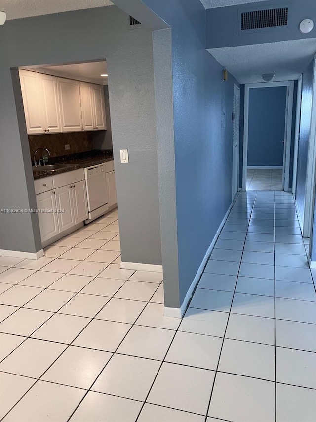 hallway with sink, a textured ceiling, and light tile patterned floors