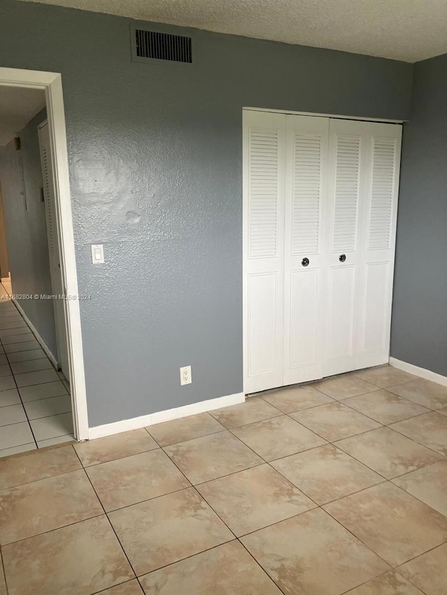 unfurnished bedroom with a closet and light tile patterned floors