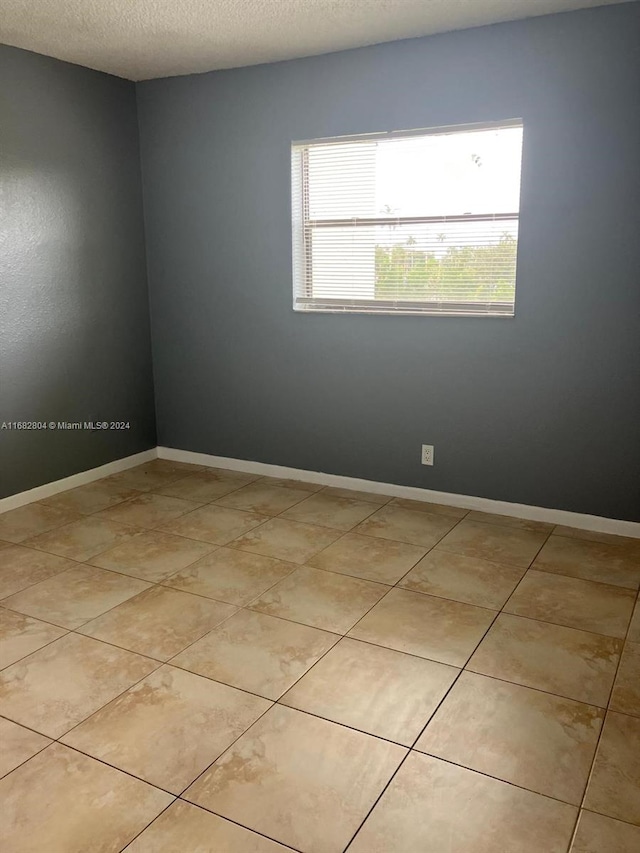 unfurnished room featuring a textured ceiling and light tile patterned floors