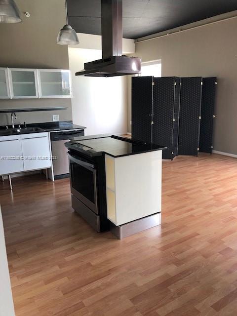 kitchen featuring sink, dishwasher, island exhaust hood, decorative light fixtures, and hardwood / wood-style flooring