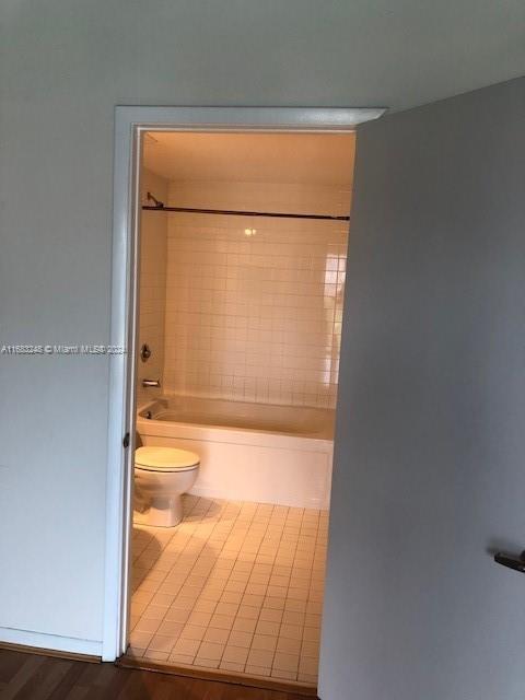 bathroom with toilet, tiled shower / bath combo, and tile patterned floors