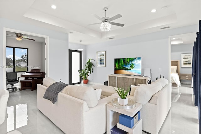 living room with a raised ceiling and ceiling fan