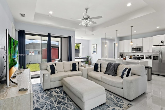 living room featuring a raised ceiling and ceiling fan