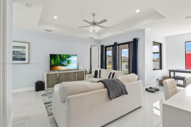 living room featuring a tray ceiling and ceiling fan