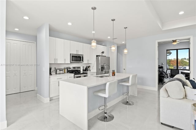 kitchen featuring pendant lighting, a kitchen island with sink, ceiling fan, white cabinetry, and stainless steel appliances