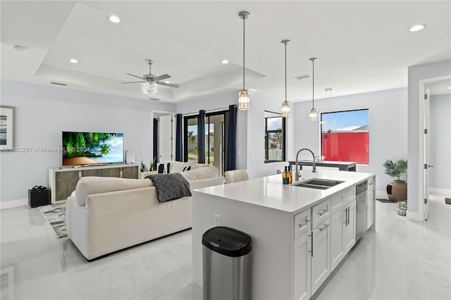 kitchen featuring stainless steel dishwasher, a raised ceiling, sink, white cabinetry, and an island with sink