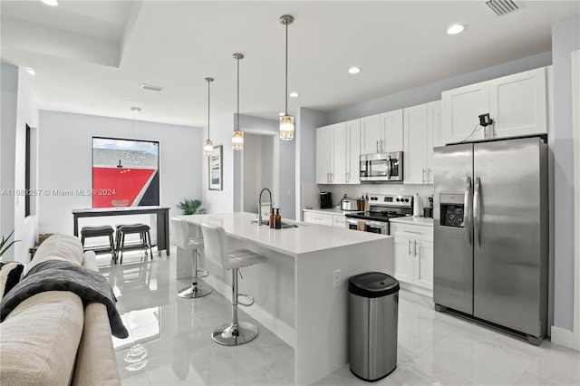 kitchen with a kitchen island with sink, white cabinets, hanging light fixtures, sink, and appliances with stainless steel finishes