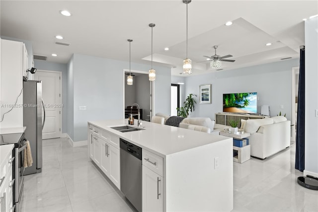 kitchen featuring white cabinetry, sink, an island with sink, a tray ceiling, and appliances with stainless steel finishes