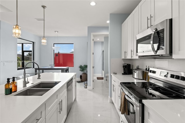 kitchen with white cabinets, decorative light fixtures, stainless steel appliances, and sink