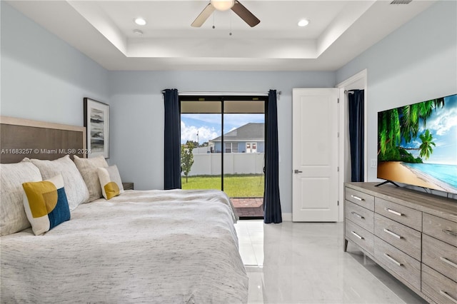 bedroom with ceiling fan, access to outside, and a tray ceiling