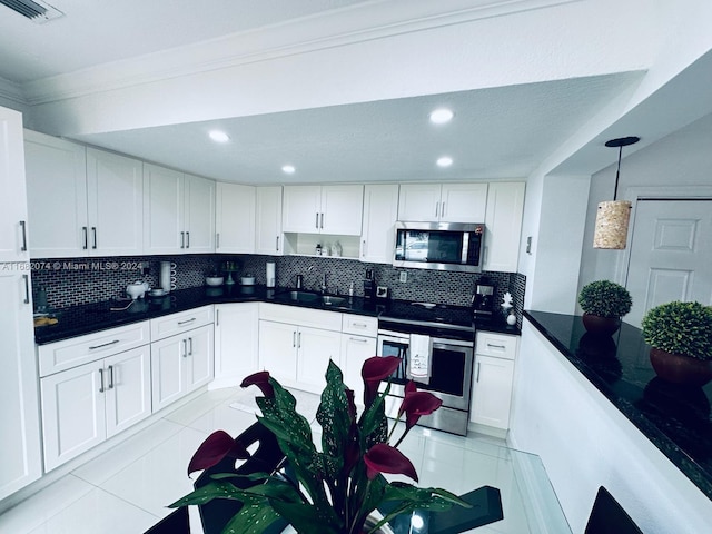 kitchen with backsplash, appliances with stainless steel finishes, light tile patterned floors, hanging light fixtures, and white cabinets