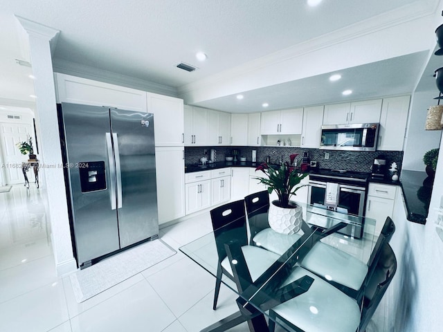 kitchen featuring tasteful backsplash, white cabinets, light tile patterned flooring, and stainless steel appliances