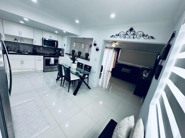 kitchen featuring white cabinets, decorative backsplash, ornamental molding, ceiling fan, and appliances with stainless steel finishes