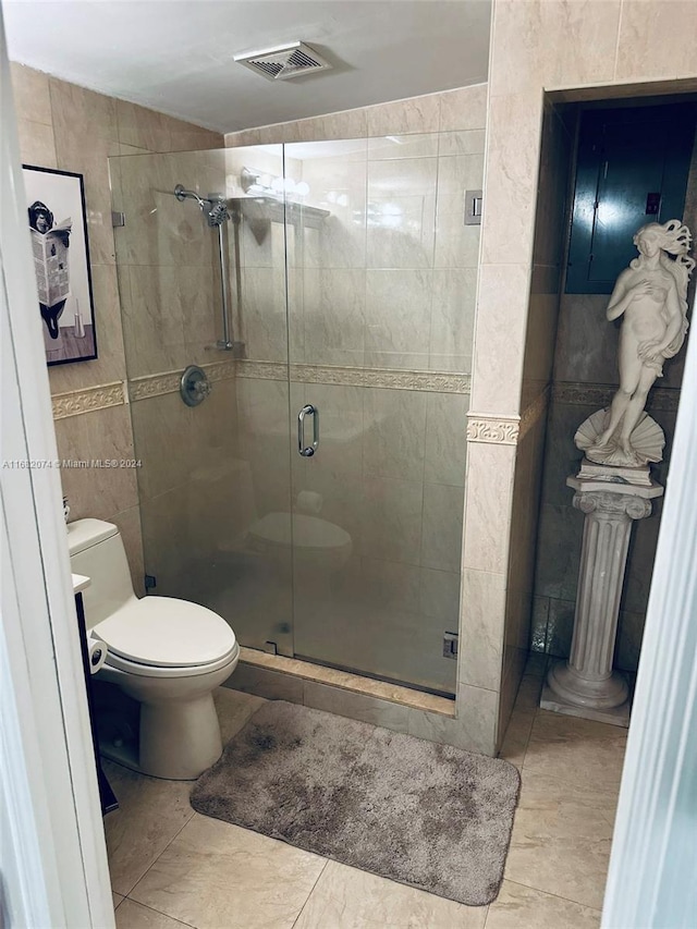 bathroom with toilet, an enclosed shower, and tile walls