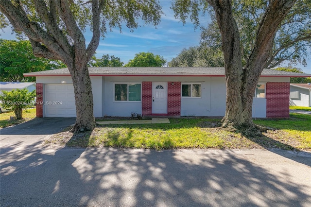 single story home featuring a garage and a front lawn