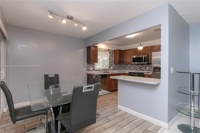 2510 SW Natura Blvd, Deerfield Beach, FL 33441 - kitchen with appliances with stainless steel finishes, tasteful backsplash, light wood-style floors, brown cabinetry, and a textured ceiling