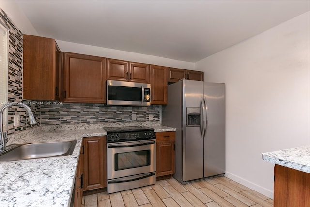 2510 SW Natura Blvd, Deerfield Beach, FL 33441 - kitchen with appliances with stainless steel finishes, light wood-style flooring, tasteful backsplash, and brown cabinetry