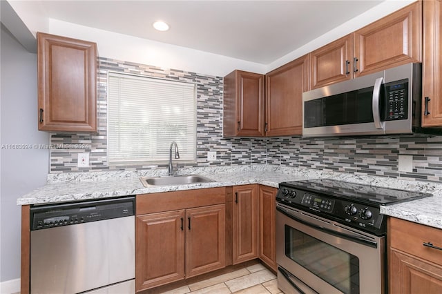 kitchen featuring light stone counters, light tile patterned flooring, stainless steel appliances, backsplash, and sink