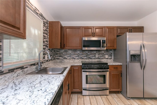 2510 SW Natura Blvd, Deerfield Beach, FL 33441 - kitchen with appliances with stainless steel finishes, decorative backsplash, brown cabinets, light wood-type flooring, and light stone countertops