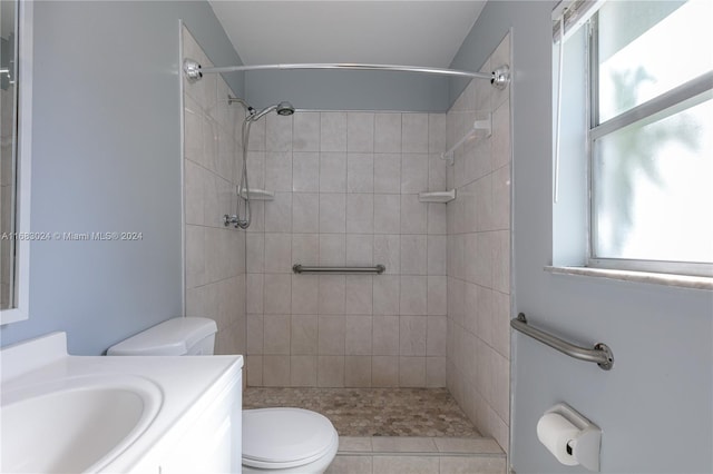 bathroom featuring tiled shower, tile patterned flooring, vanity, and toilet