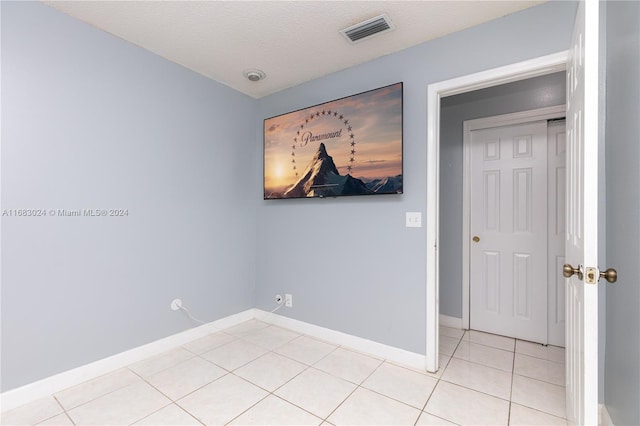 empty room with a textured ceiling and light tile patterned floors