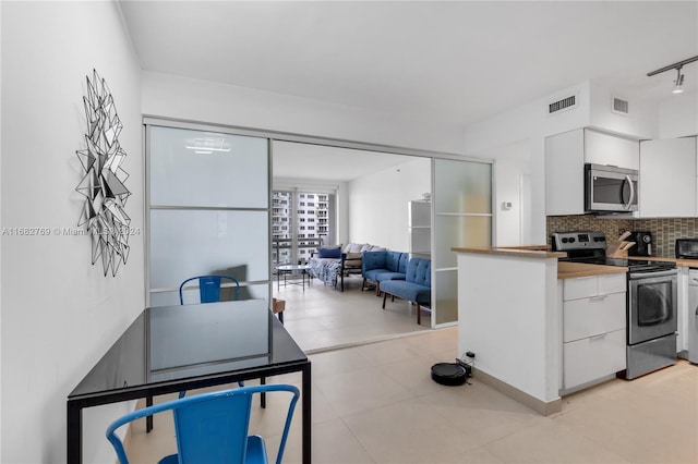 kitchen featuring track lighting, white cabinets, stainless steel appliances, and backsplash