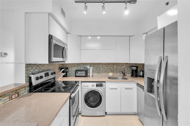 kitchen featuring washer / clothes dryer, white cabinets, backsplash, appliances with stainless steel finishes, and sink