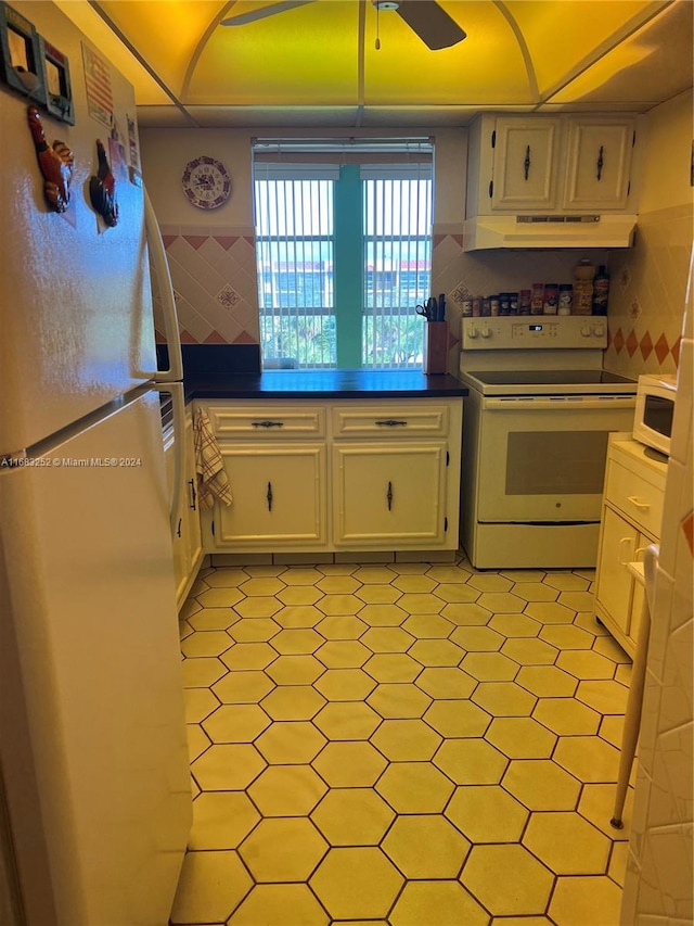 kitchen featuring tile walls, white cabinets, and white appliances