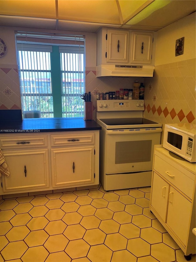 kitchen featuring white appliances, white cabinetry, and tile walls