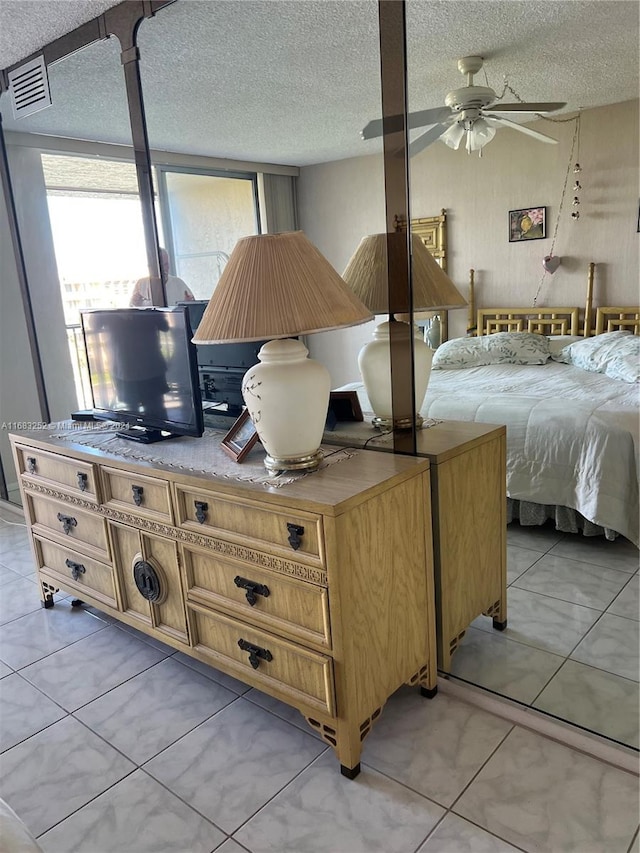 tiled bedroom featuring ceiling fan and a textured ceiling