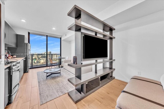 living room with expansive windows, a water view, and light hardwood / wood-style floors