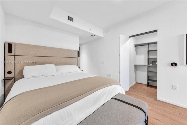 bedroom with a walk in closet, hardwood / wood-style floors, and a closet