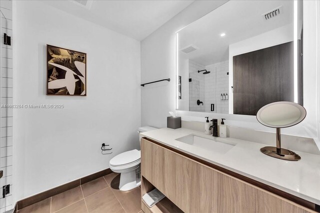 bathroom featuring tile patterned flooring, a shower with door, vanity, and toilet