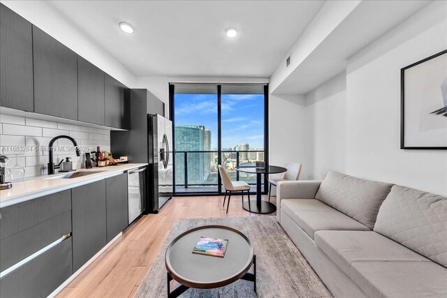 living room featuring light wood-type flooring, expansive windows, and sink