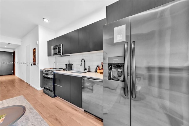 398 NE 5th St Unit 3707, Miami, FL 33132 - kitchen with stainless steel appliances, dark cabinetry, light wood finished floors, backsplash, and light countertops