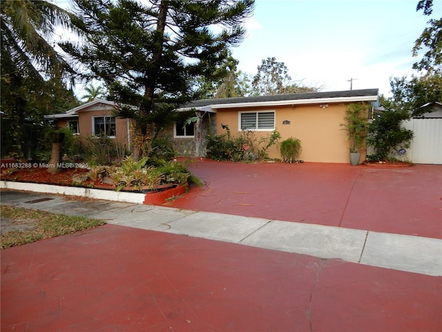 ranch-style house featuring fence and stucco siding