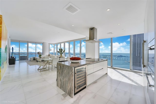 kitchen featuring wine cooler, island exhaust hood, white cabinets, and expansive windows