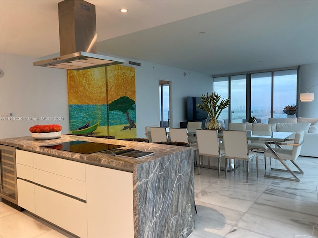 kitchen with wine cooler, white cabinets, a wall of windows, island range hood, and black electric stovetop