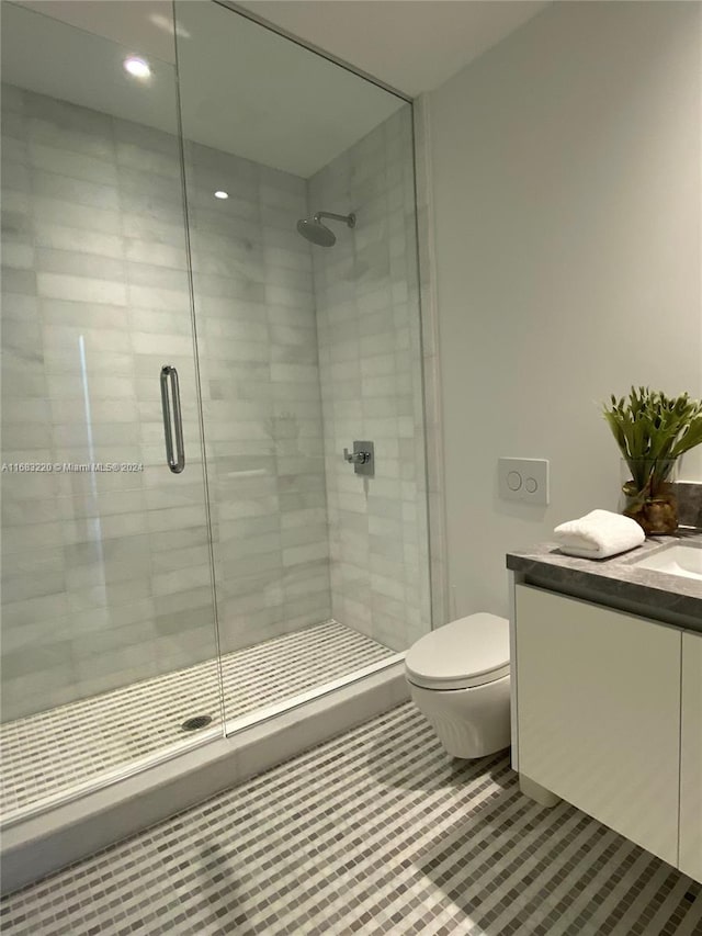 bathroom featuring vanity, a shower with shower door, toilet, and tile patterned floors