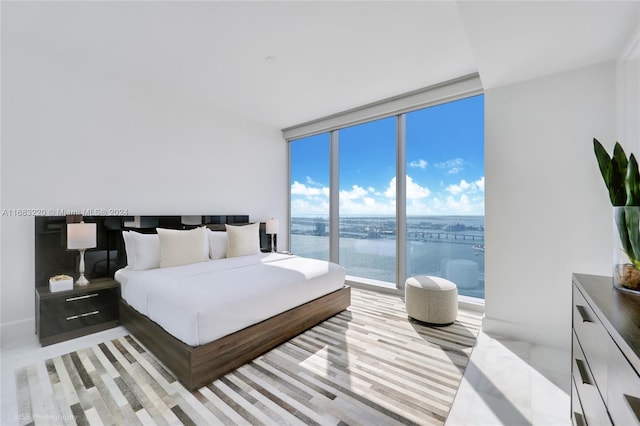 bedroom with floor to ceiling windows and a water view