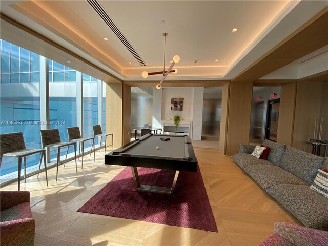 game room featuring light parquet floors, a tray ceiling, and pool table