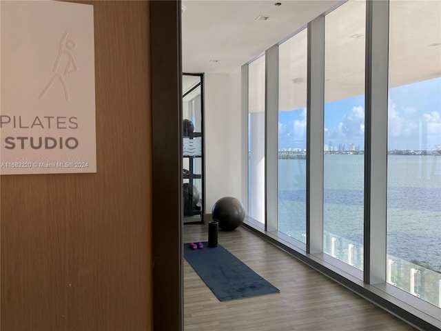 hallway featuring expansive windows, a water view, and hardwood / wood-style flooring