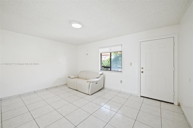 unfurnished room with a textured ceiling and light tile patterned flooring